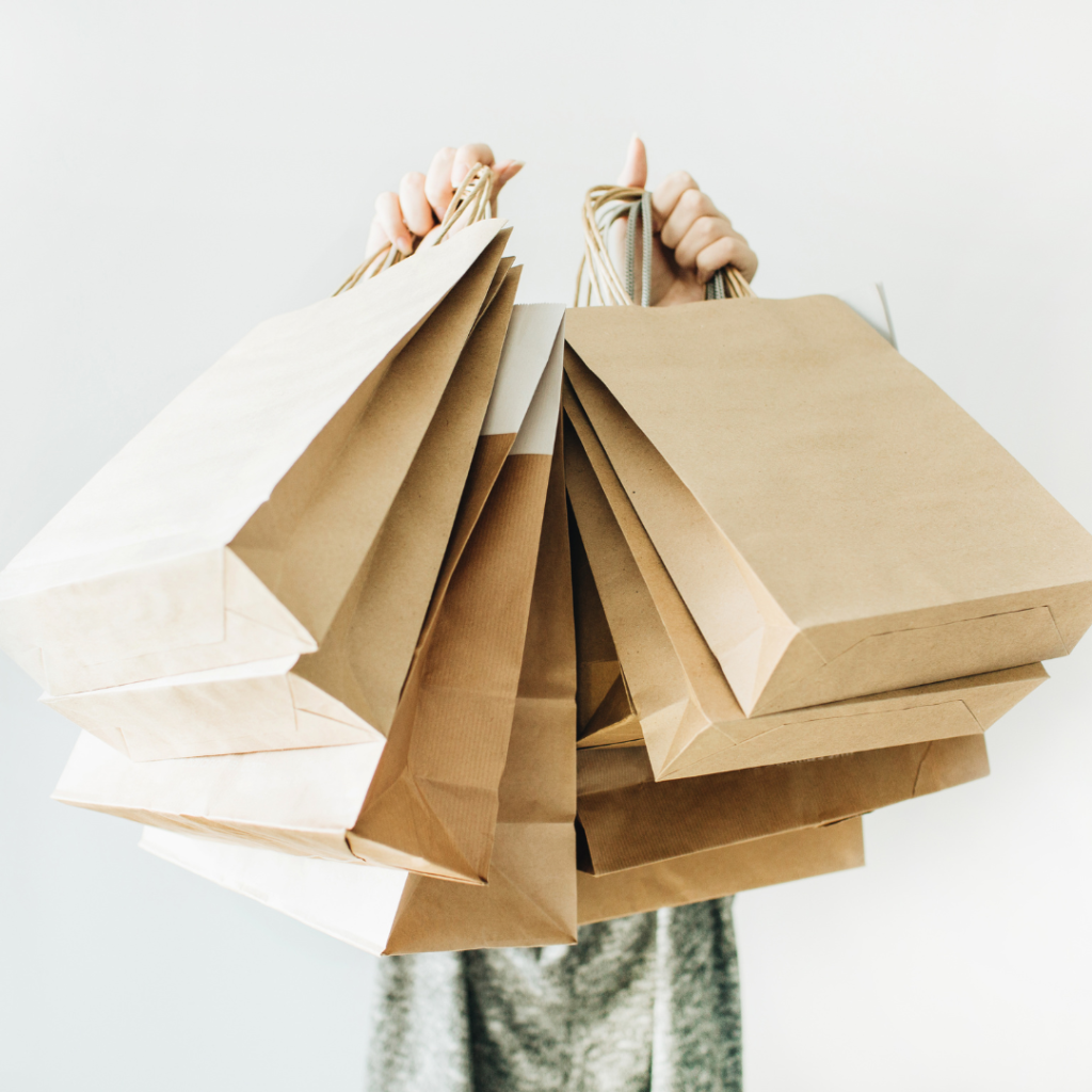 A person holds up several brown paper bags, displaying them prominently in front.